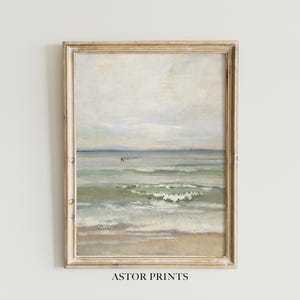 Könnte beinhalten: Ein gerahmter Vintage-Druck einer Meereslandschaft. Das Kunstwerk zeigt eine Strandszene mit Wellen, Sand und einem bewölkten Himmel. Der Rahmen ist aus hellem, verwittertem Holz. Der Text "ASTOR PRINTS" ist unten im Bild aufgedruckt.