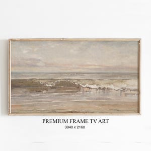 Könnte beinhalten: Gerahmtes Landschaftsgemälde einer Strandszene. Das Kunstwerk zeigt einen ruhigen Ozean mit Wellen, die am Ufer brechen. Die Farbpalette umfasst gedämpfte Töne von Beige, Grau und Blau. Der Text "PREMIUM FRAME TV ART" und die Abmessungen stehen unten.