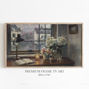 Könnte beinhalten: Gerahmtes Gemälde einer Stilllebenszene. Im Hintergrund ein Fenster mit Blick auf Gebäude. Eine Schreibtischlampe, ein offenes Buch, eine Kerze und Vasen mit Blumen stehen auf einem Holztisch. Der Text "PREMIUM FRAME TV ART" steht unten.