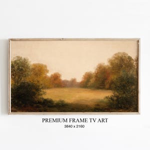 Könnte beinhalten: Gerahmtes Landschaftsgemälde mit einer friedlichen Wiesenlandschaft. Das Kunstwerk zeigt ein Feld mit goldenem Gras, umgeben von Bäumen mit Herbstlaub in Grün-, Gelb- und Rottönen. Der Himmel ist ein weiches, warmes Beige. Der Text "PREMIUM FRAME TV ART" steht unten.
