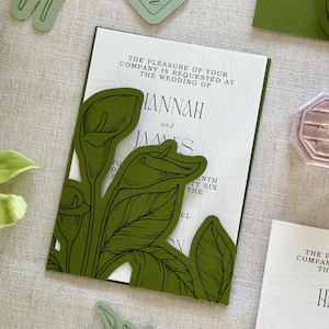 Pode incluir: Convite de casamento com um design floral verde. O convite apresenta os nomes "Hannah" e "James" e o texto "O prazer da sua companhia é solicitado no casamento de". Recortes florais verdes adicionais são visíveis.