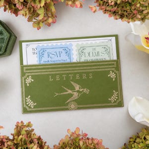 May include: A rectangular olive green envelope with the word LETTERS and a gold swallow illustration printed on the front. Inside, two white cards are visible, one with a blue RSVP stamp design and one with a green THE DETAILS stamp design.