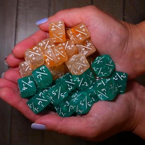 Könnte beinhalten: Ein Set aus drei Keramikbechern mit gesprenkelter, matter Oberfläche. Die Becher sind in Creme-, Hellgrau- und Dunkelgrautönen gehalten. Jeder Becher hat ein schlichtes, minimalistisches Design, ideal für Kaffee oder Tee.