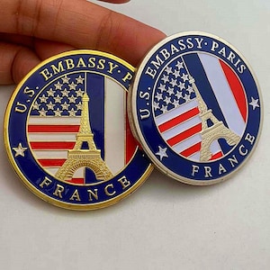 Op de afbeelding: Een witte keramische mok met een zwart handvat en de tekst "But First, Coffee" in een zwarte, vette letter. De mok staat op een wit oppervlak. De mok is ongeveer 10 cm hoog.