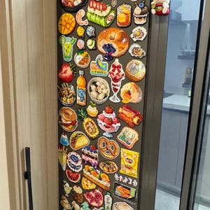 May include: A refrigerator door covered in colorful food-themed magnets. The magnets depict various foods and drinks, including soda cans, sushi, ice cream, and pastries. A cute bunny magnet is also visible.