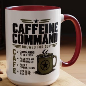 May include: A white ceramic mug with a dark red interior and handle. The front features black text reading CAFFEINE COMMAND BREWED FOR DUTY, with a list defining CAFE as Commands Attention, Accepts No Surrender, Fuels Operations, Expects Results.