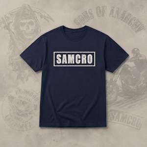 Peut inclure: Un t-shirt bleu marine à manches courtes avec un motif rectangulaire blanc portant le texte SAMCRO dans une police vieillie et usée au centre de la poitrine. Le vêtement présente un col rond et une coupe standard avec des ourlets droits.