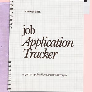 Peut inclure: Un cahier à spirales avec du papier quadrillé. La couverture affiche "WARDIE INC." en haut, avec "job Application Tracker" dans une police élégante. En dessous, on peut lire "organize applications, track follow ups". Le cahier est posé sur une surface rose.