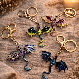 Peut inclure: Plusieurs porte-clés dragons colorés avec des attaches dorées. Les dragons présentent des détails complexes et des ailes vibrantes dans des tons de bleu, vert, violet et rose. Chaque porte-clés est équipé d'un mousqueton.