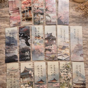 May include: A set of rectangular bookmarks featuring Japanese landscape illustrations. Each bookmark depicts a different scene with temples, cherry blossoms, and Japanese text. The colour scheme includes soft pinks, greens, and blues.