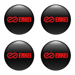 May include: Four glossy black circular emblems featuring the word "ENKEI" in red, alongside a red infinity symbol. The emblems are arranged in a square pattern against a white backdrop.