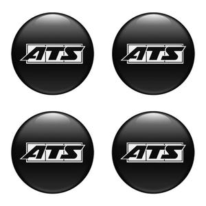 Può includere: Quattro emblemi circolari neri e lucidi. Ogni emblema presenta le lettere bianche "ATS" all'interno di un telaio rettangolare bianco. Si tratta probabilmente di accessori automobilistici, forse per ruote o marchi di veicoli.