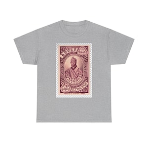 May include: A heather gray t-shirt featuring a maroon graphic of a vintage Ethiopian stamp. The stamp depicts a crowned figure and includes text in Amharic and French. The shirt is made of a soft, comfortable material.