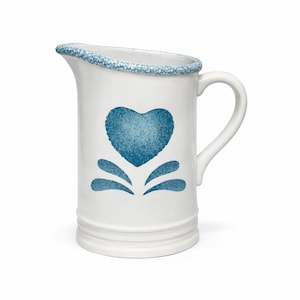 Peut inclure: Pichet en céramique blanche avec un motif de cœur bleu et un bord bleu moucheté. Le pichet a une anse et un bec verseur. Le cœur est entouré de gouttes d'eau bleues stylisées. Un article de cuisine décoratif.