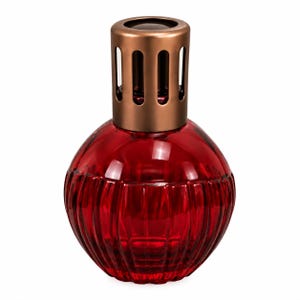 May include: A round, deep red glass fragrance lamp with a ribbed, vertical texture. The vessel is topped with a cylindrical, metallic bronze-coloured cap featuring vertical cutouts around the perimeter to allow for air circulation.