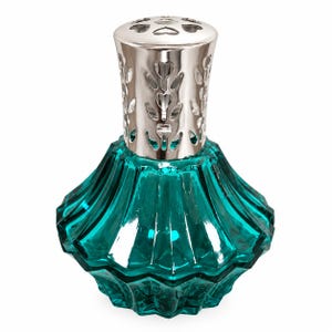 May include: A teal glass fragrance lamp with a faceted, diamond-like body and a wide, flared base. The top features a polished silver-coloured metal cap with intricate, heart-shaped cutouts arranged in a vertical pattern around the neck.