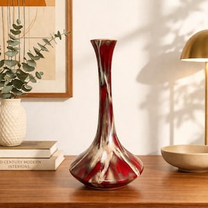 Peut inclure: Un vase décoratif avec une base évasée et un col fin. Le vase présente une finition brillante avec une palette de couleurs rouge, blanche et marron. Un élément de décoration intérieure élégant, idéal pour exposer des fleurs ou comme pièce d'accent.