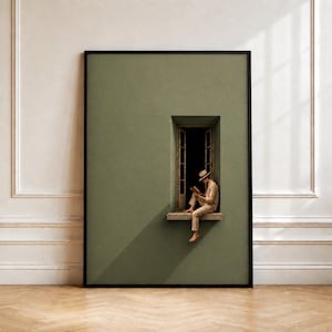Pode incluir: Uma impressão de arte emoldurada apresentando uma parede verde-sálvia sólida com uma única janela aberta. Uma pessoa vestindo camisa, calças e chapéu de cor clara está sentada no parapeito da janela lendo um livro. Sombras diagonais.