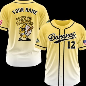 Puede incluir: Camiseta de b&eacute;isbol amarilla con ribete negro y la palabra "Bananas" en cursiva en el pecho. El n&uacute;mero "12" est&aacute; debajo de la palabra. La parte posterior de la camiseta tiene las palabras "Your Name" encima de "Let's Go Bananas" con un pl&aacute;tano de dibujos animados.