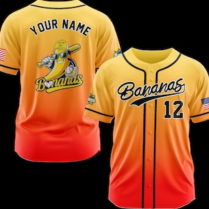 K&ouml;nnte beinhalten: Zwei Baseball-Trikots mit gelb-orange-rotem Farbverlauf. Eines hat "YOUR NAME" auf dem R&uuml;cken und eine Bananenfigur mit Sonnenbrille und Baseballschl&auml;ger. Das andere hat "Bananas" und die Nummer "12". Beide haben die amerikanische Flagge.