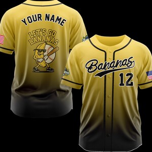 Puede incluir: Camiseta de b&eacute;isbol amarilla y negra con la palabra "Bananas" en escritura en el pecho y el n&uacute;mero 12. La camiseta tiene un dise&ntilde;o degradado y presenta un parche de la bandera estadounidense en la manga. La parte posterior de la camiseta dice "Your Name" y "Let's Go Bananas".