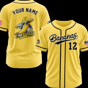 K&ouml;nnte beinhalten: Gelbes Baseball-Trikot mit schwarzem Besatz und dem Wort "Bananas" in Schreibschrift. Die Nummer 12 befindet sich auf der Vorderseite. Auf der R&uuml;ckseite befindet sich eine Bananenfigur mit Sonnenbrille und Baseballschl&auml;ger. Eine amerikanische Flagge befindet sich auf dem &Auml;rmel.