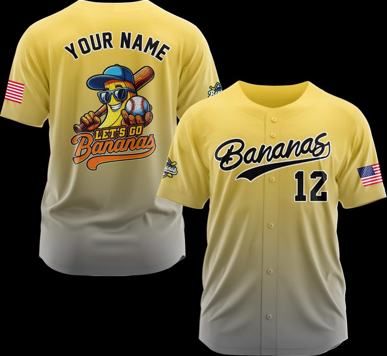 Puede incluir: Dos camisetas de b&eacute;isbol amarillas. Una presenta un pl&aacute;tano de dibujos animados con gafas de sol, un bate de b&eacute;isbol y una pelota de b&eacute;isbol. El texto "LET'S GO Bananas" est&aacute; debajo del pl&aacute;tano. La otra camiseta tiene "Bananas" en escritura y el n&uacute;mero "12". Ambas tienen una bandera estadounidense.