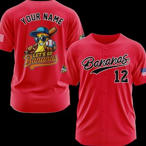 Puede incluir: Camiseta de b&eacute;isbol roja con "Bananas" en cursiva y el n&uacute;mero 12. La parte posterior de la camiseta presenta un pl&aacute;tano de dibujos animados con gafas de sol y una gorra de b&eacute;isbol, sosteniendo un bate y una pelota, con el texto "Let's Go Bananas".