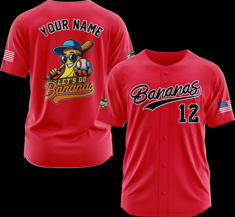 Puede incluir: Camiseta de b&eacute;isbol roja con "Bananas" en cursiva y el n&uacute;mero 12. La parte posterior de la camiseta presenta un pl&aacute;tano de dibujos animados con gafas de sol y una gorra de b&eacute;isbol, sosteniendo un bate y una pelota, con el texto "Let's Go Bananas".