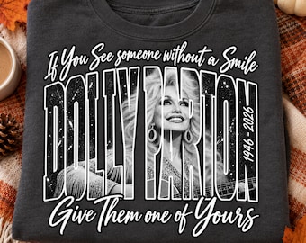 Può includere: Una felpa girocollo grigio scuro con una grafica in bianco e nero di Dolly Parton che suona la chitarra. Il testo recita: If You See someone without a Smile DOLLY PARTON 1946-2026 Give Them one of Yours in caratteri bianchi.