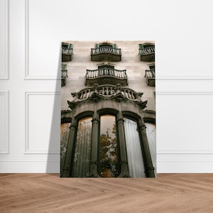 May include: A photograph of a building facade with elaborate architectural features. The building has several balconies with wrought iron railings and arched windows. The windows display the Dior logo. The building is constructed from light-coloured stone.