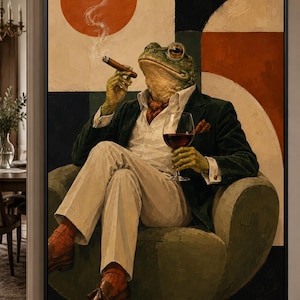 May include: A framed wall art print depicting a frog with a human-like posture sitting in a green armchair. The frog wears a dark green blazer, white shirt, and light trousers, holding a cigar with rising smoke and a glass of red wine.