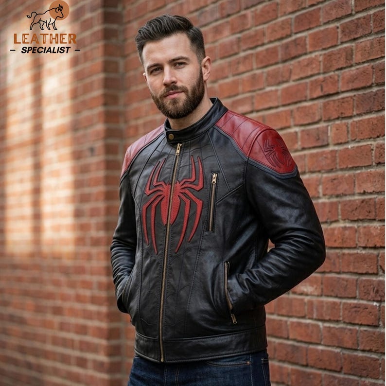 May include: A black leather jacket featuring a prominent red spider emblem on the chest, red shoulder panels, a stand-up collar, a full-length front zip, and two zipped chest pockets. The design includes intricate stitching and panel detailing.