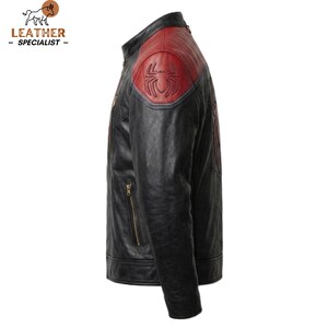 May include: A black leather jacket featuring a red shoulder panel with an embossed spider emblem. The jacket includes a stand-up collar, a vertical zipped pocket on the chest, and subtle stitched detailing along the sleeves and side panels.