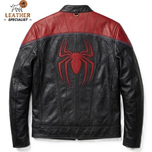May include: A black and red leather jacket featuring a prominent red spider emblem centred on the back. The jacket has a stand-up collar with a small metal ring detail, long sleeves, and a panelled construction with visible stitching throughout.