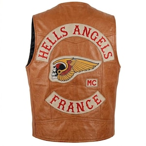 Peut inclure: Gilet en cuir marron avec le logo "Hells Angels" au dos. Le logo représente une tête de mort ailée et le mot "France" en dessous. Le gilet est de style motard classique.