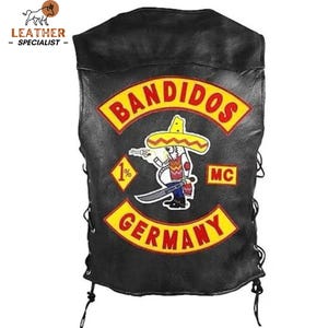 Pode incluir: Um colete de couro preto com atacadores laterais e um grande emblema nas costas. O emblema apresenta o texto BANDIDOS em vermelho sobre um fundo amarelo, uma figura de desenho animado com um sombrero e uma espada, um emblema 1% e GERMANY.
