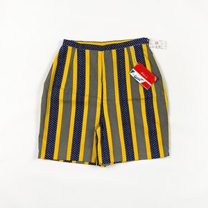 May include: High-waisted shorts with a striking pattern. The shorts feature vertical stripes in yellow and grey, interspersed with navy blue stripes dotted with white. A tag with text is attached to the shorts.