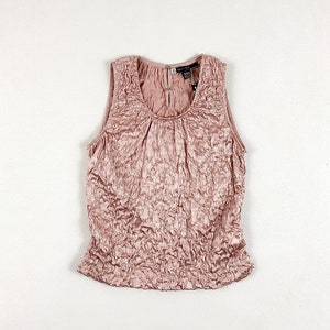 May include: A sleeveless, blush-colored, crinkled satin top with a scoop neck.