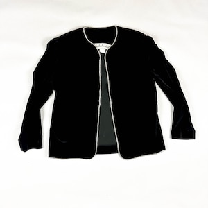 May include: A black velvet jacket with a rhinestone trim along the edges. The jacket has long sleeves and a tailored fit. The label inside the jacket reads "Nicole Miller Studio".