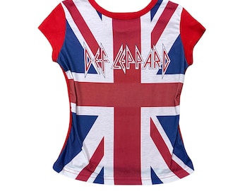 May include: A red, white, and blue t-shirt featuring the Union Jack flag design. The shirt has red sleeves and a crew neck. The band name "Def Leppard" is printed across the center of the shirt in a white, stylized font.