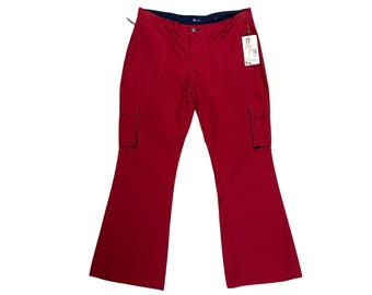 May include: Red cargo pants with a flared leg design. The pants have two cargo pockets and a dark blue waistband. A price tag is attached to the pants.