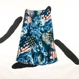 May include: A-line skirt with a patriotic design. The skirt features a blue tie-dye pattern with American flag elements, including red and white stripes and white stars. The fabric has a silky sheen.