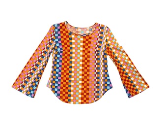 May include: A long-sleeved top with a vibrant, geometric pattern. The top features a scoop neck and flared sleeves. The color scheme includes orange, red, blue, pink, and white squares arranged in vertical stripes.
