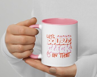 May include: White ceramic mug with a pink interior and handle. The mug features the text "Let's Double Click On That" in red and pink bubble letters. A computer mouse icon is also included.