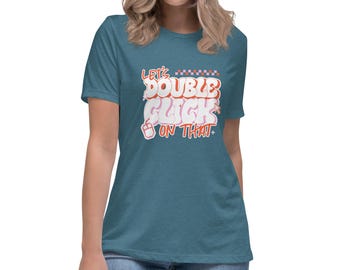 May include: Teal short-sleeve t-shirt with the text "Let's Double Click On That" in a retro font. The text is in white, red, and orange. The shirt is made of a soft material.