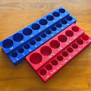 Peut inclure: Un plateau organisateur de forets bleu et un rouge de forme rectangulaire. Le plateau bleu présente des trous numérotés de 6 à 24. Le plateau rouge comporte des étiquettes en pouces fractionnaires allant de 1/4 à 1.