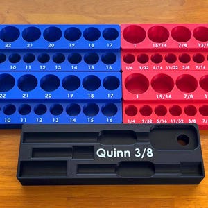May include: Two blue and two red rectangular socket organizers with numbered slots for metric and imperial sizes, accompanied by a black rectangular tray labeled Quinn 3/8 with recessed compartments for tool storage.