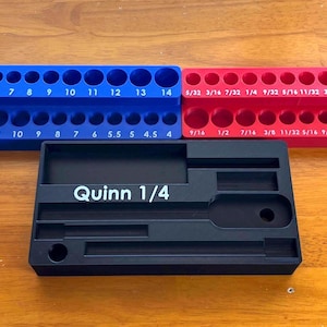 May include: A blue metric socket organizer with sizes 4 through 14, a red imperial socket organizer with sizes 5/32 through 9/16, and a black rectangular Quinn 1/4 drive socket tray with various recessed slots for tool storage.