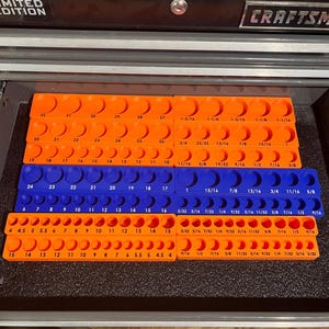 May include: An open toolbox drawer with orange and blue socket organizers. The organizers hold various sockets, labeled with sizes in inches. The drawer is from the Craftsman Limited Edition collection.